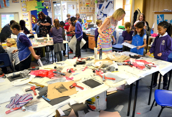 Busy classroom with three activities: exploring paint, printmaking and making rubbings