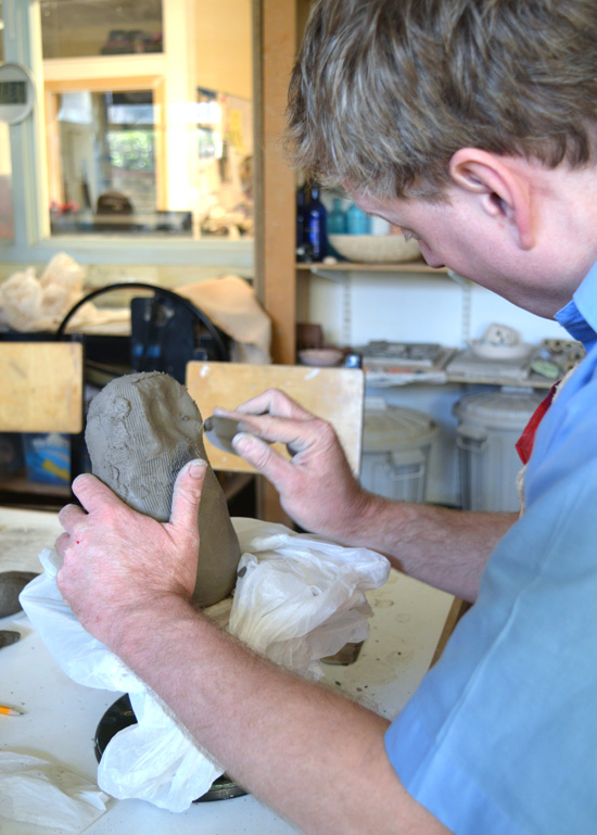 Peter works on his owl built using clay coiling techniques and now smoothing with a kidney