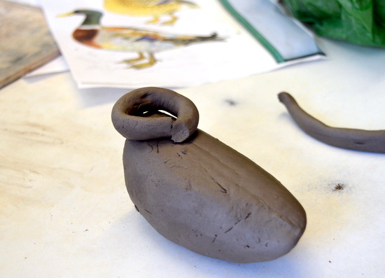 Jenny builds the neck for her duck with rolled clay for the head to sit on
