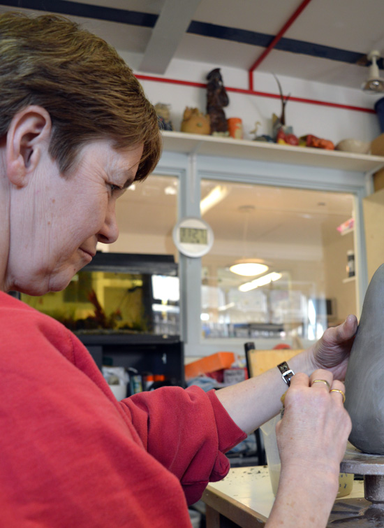 Having added the penguin's head, Janette smooths the clay with a wet sponge