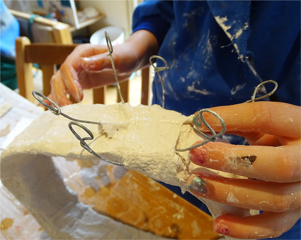 The next challenge was to find a sculptural solution to how the large genstone could be attached to the band. Some children embedded wires in the modroc to form claws