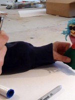 Nina takes a photo of her puppet on a devise