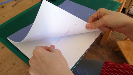 Pulling the end of thread through the middle of the book