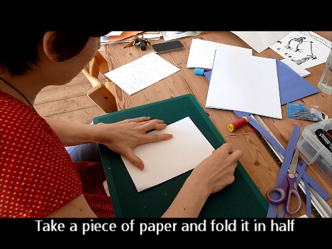 Screen shot of video above of Aurora folding paper to make a template