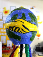 The balloon formed globe on top of the sculpture and the shaking hands school symbol
