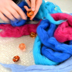 Innes chooses beads and wool and starts to experiment with threading