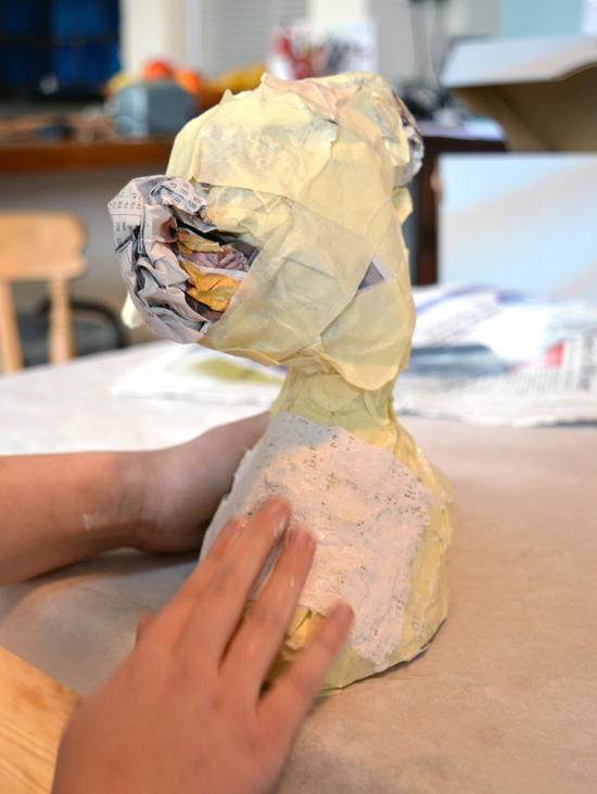 Portia then applies modroc over her masking tape and newspaper armature and uses her fingers to massage the modroc to create an even layer and form it before it dries