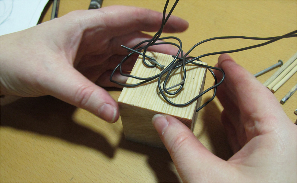 Attaching modelling wire with nail to wooden block to make an armature
