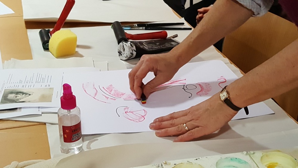 She then goes over the drawing with rainbow crayon to create areas of resistance which will repel the ink and water 