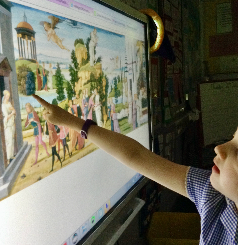 A girl looking at a painting of Cupid and Psyche on a whiteboard in a classroom and pointing at a tree