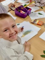 Year One boy at Hauxton Primary School drawing leaves with pastels with Pamela Stewart for Inspire