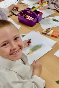 Year One boy at Hauxton Primary School drawing leaves with pastels with Pamela Stewart for Inspire