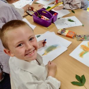 Year One boy at Hauxton Primary School drawing leaves with pastels with Pamela Stewart for Inspire