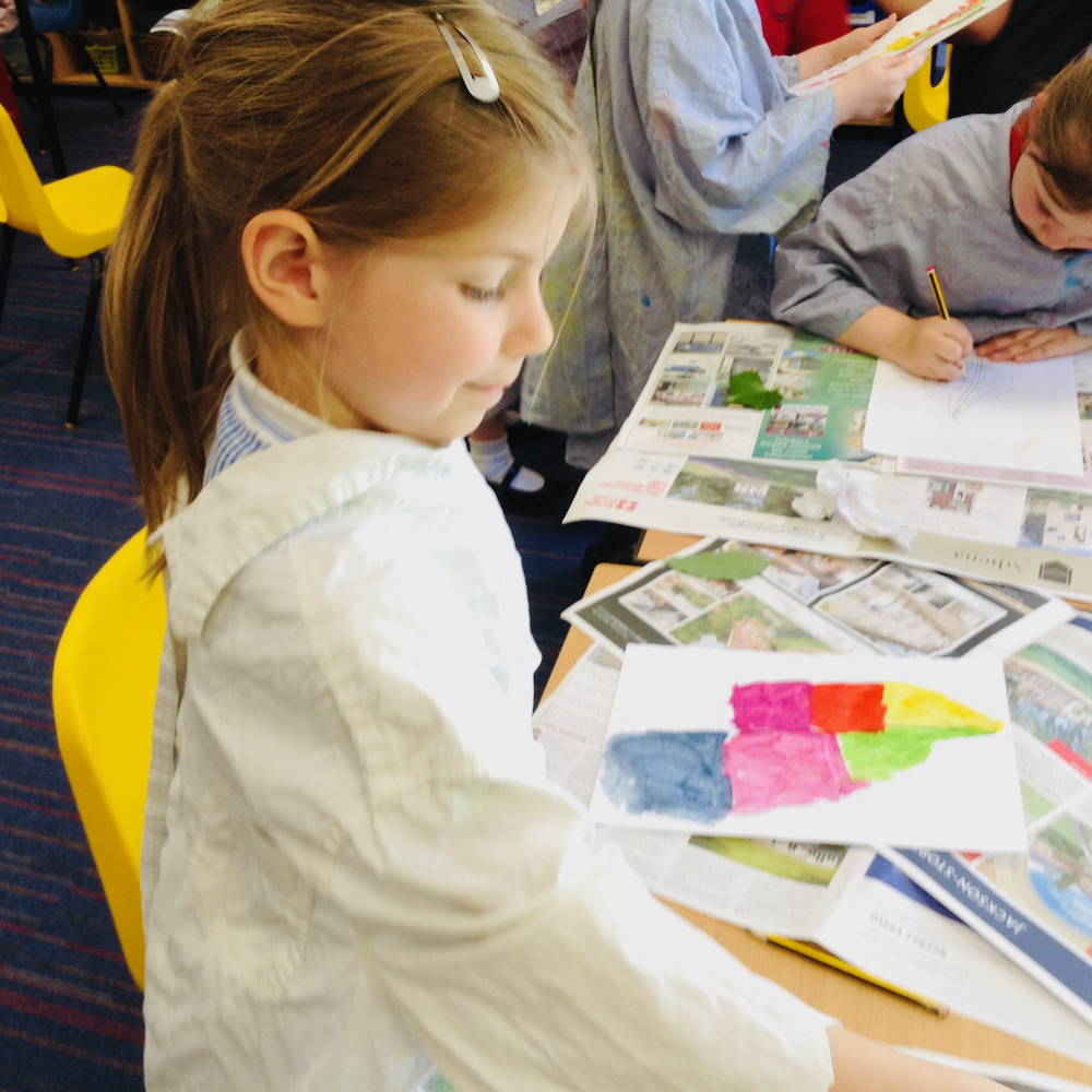 A girl paints a colourful leaf with egg tempera mixing powder paint and egg at Hauxton Primary for Inspire with Pamela Stewart