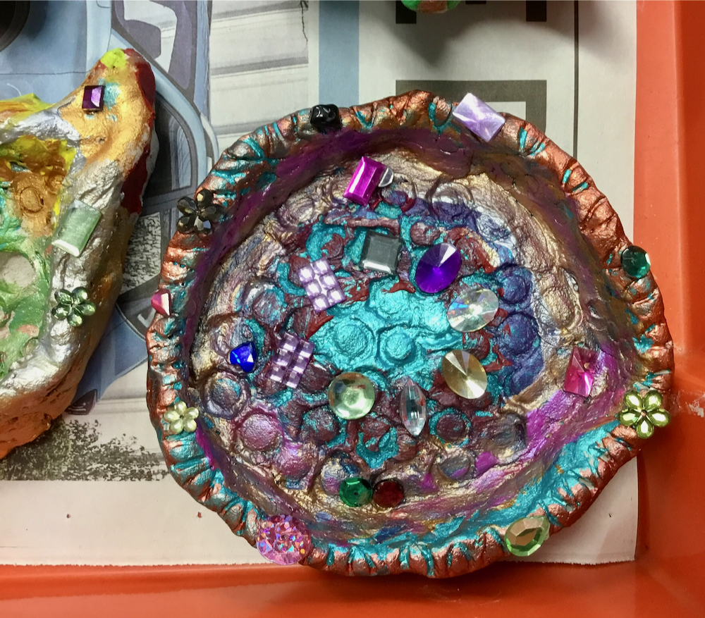 Colourful clay tray decorated with paint and coloured jewels made by a year three pupil 