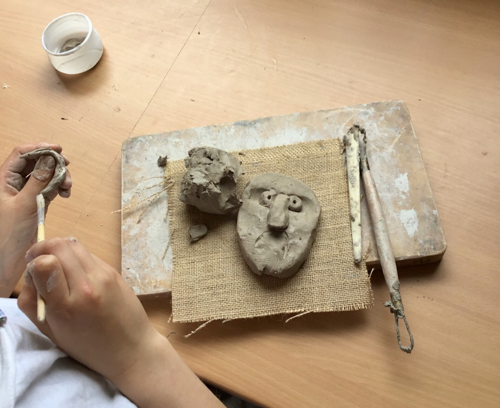 A clay head being created on a school table top by a Year Four pupil with school clay and wooden tools