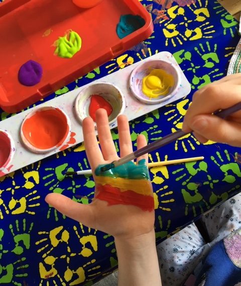 Painting rainbow stripes across hands