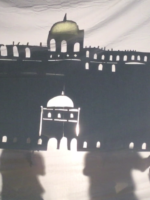 Holding up a large shadow puppet of a palace
