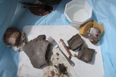 Clay, water and a fork on a table outside