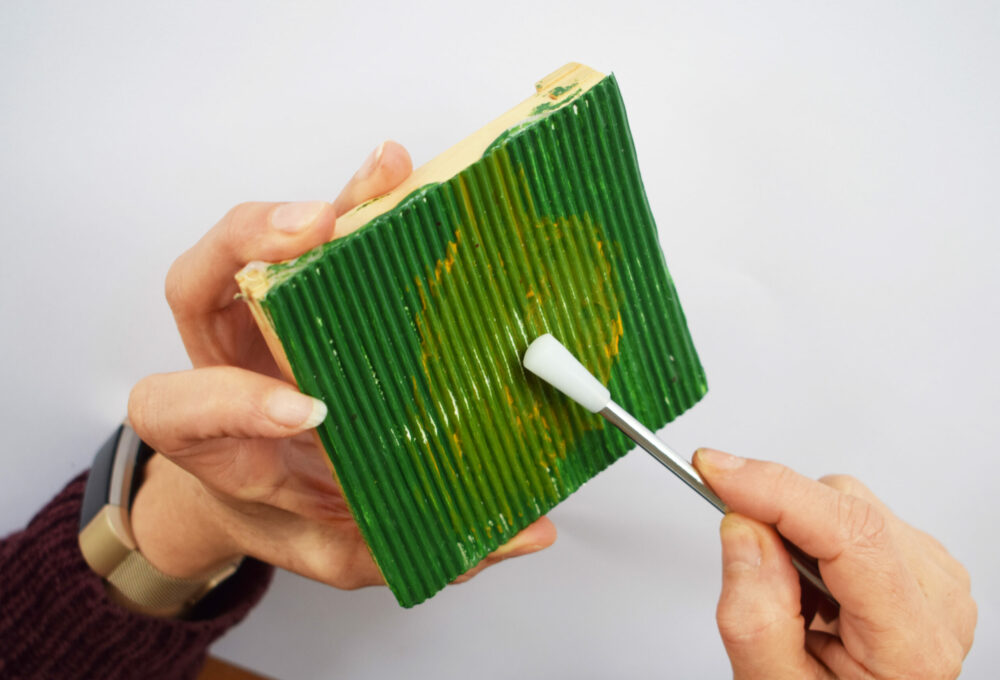 A ribbed percussion instrument with beater made from card