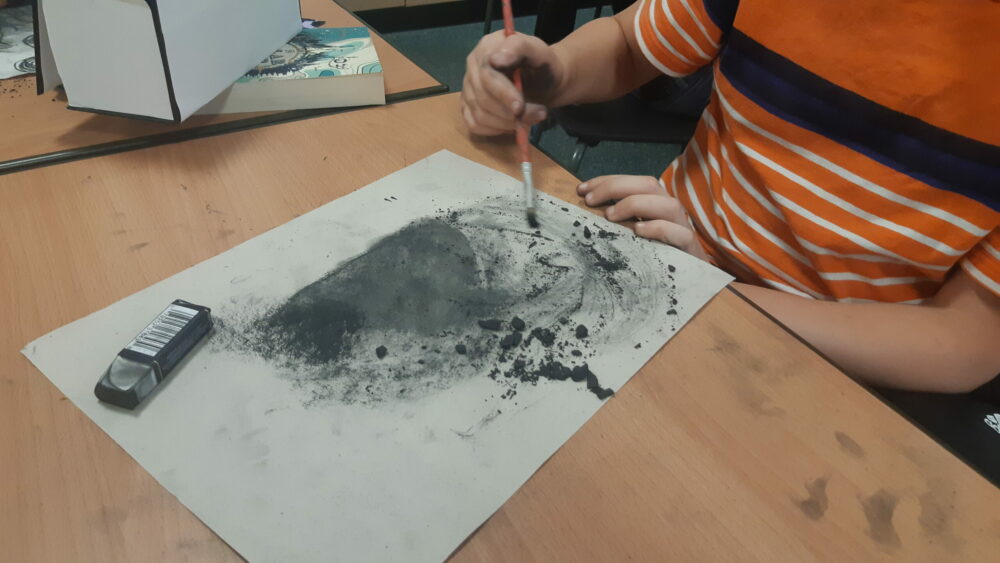 Crushing charcoal onto paper