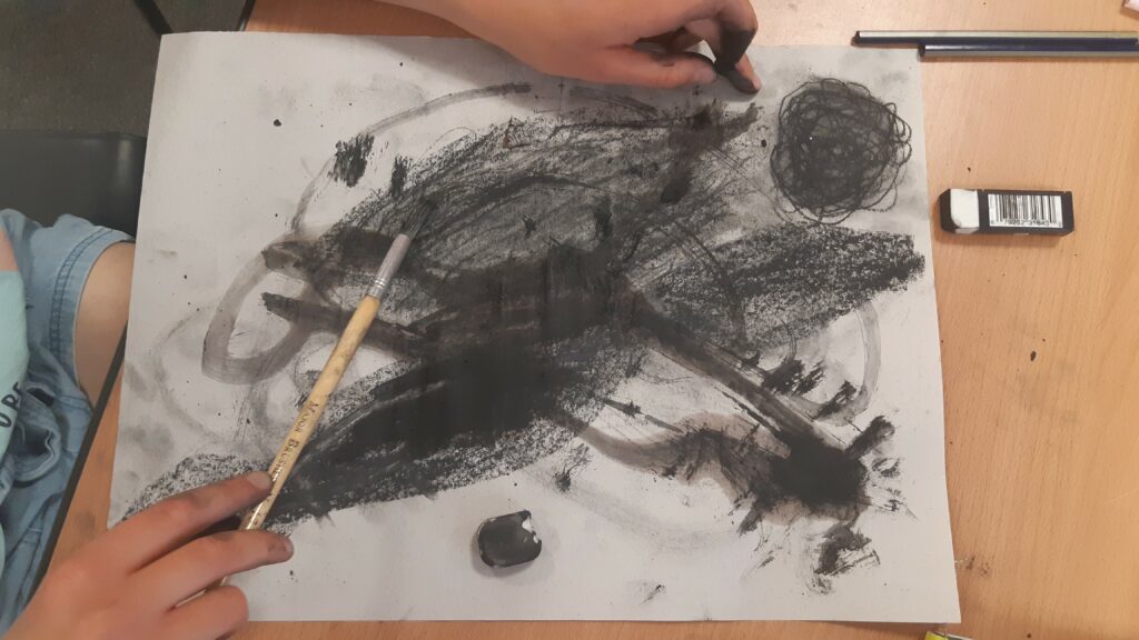 Adding water to to crushed charcoal on paper