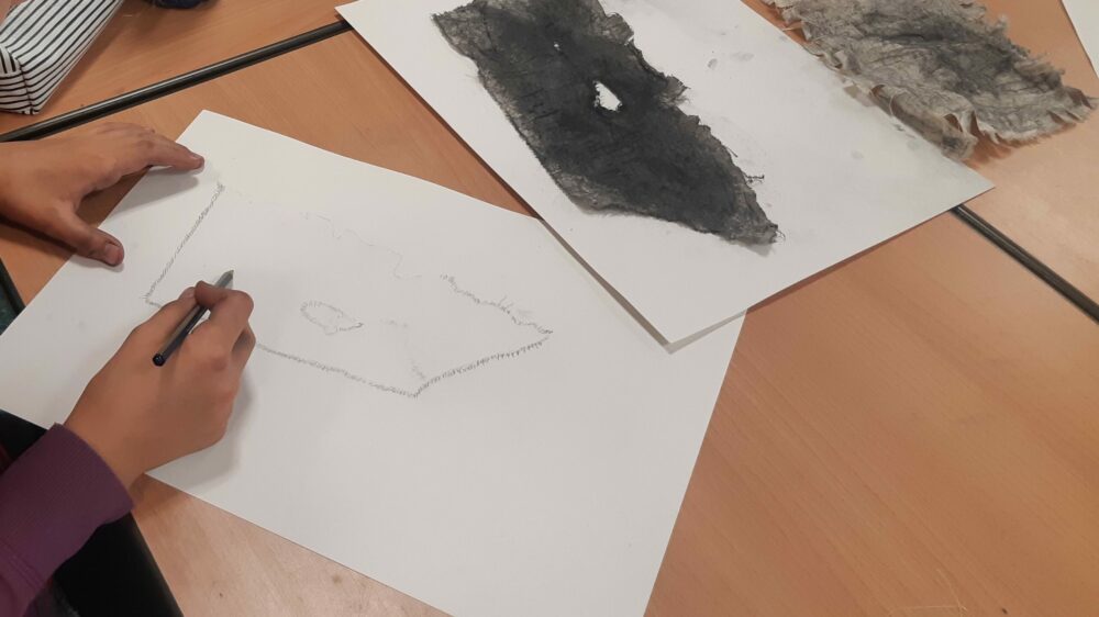 Observing a piece of fabric distressed with charcoal.