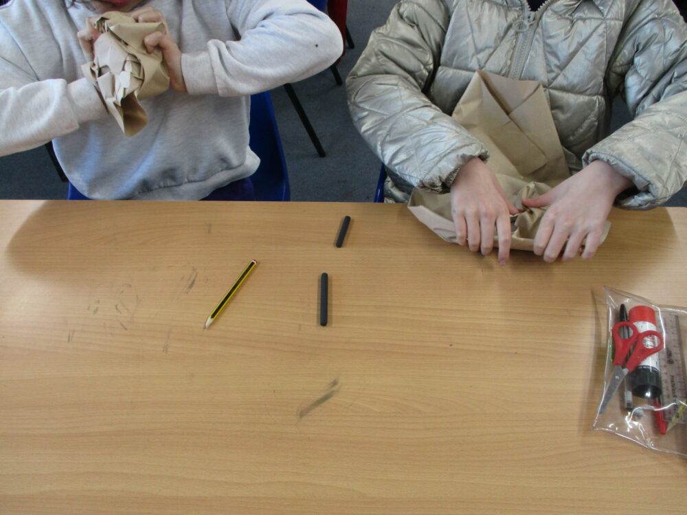 Scrunching sugar paper to make a paper cloak.