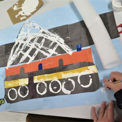 Adding detail to a collage of a boat.