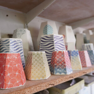 A line of ceramic pots on a shelf.