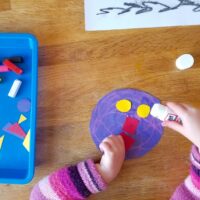 Glueing shapes onto a circle of paper.