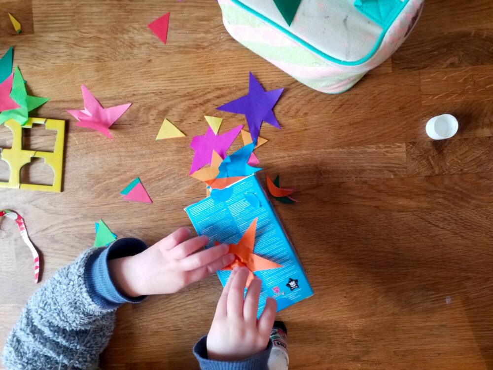 Sticking shapes onto cut out cardboard items.