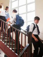 Group Of Teenage Students In Uniform Walking Between Classrooms