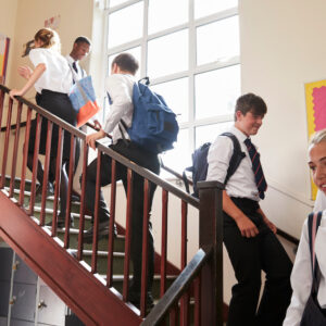 Group Of Teenage Students In Uniform Walking Between Classrooms