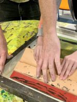 Teacher assisting child in screenprinting