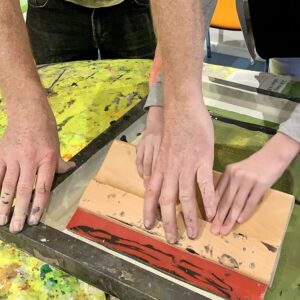Teacher assisting child in screenprinting