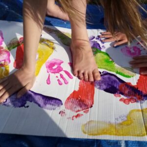 Children making colourful hand and footprints with paint