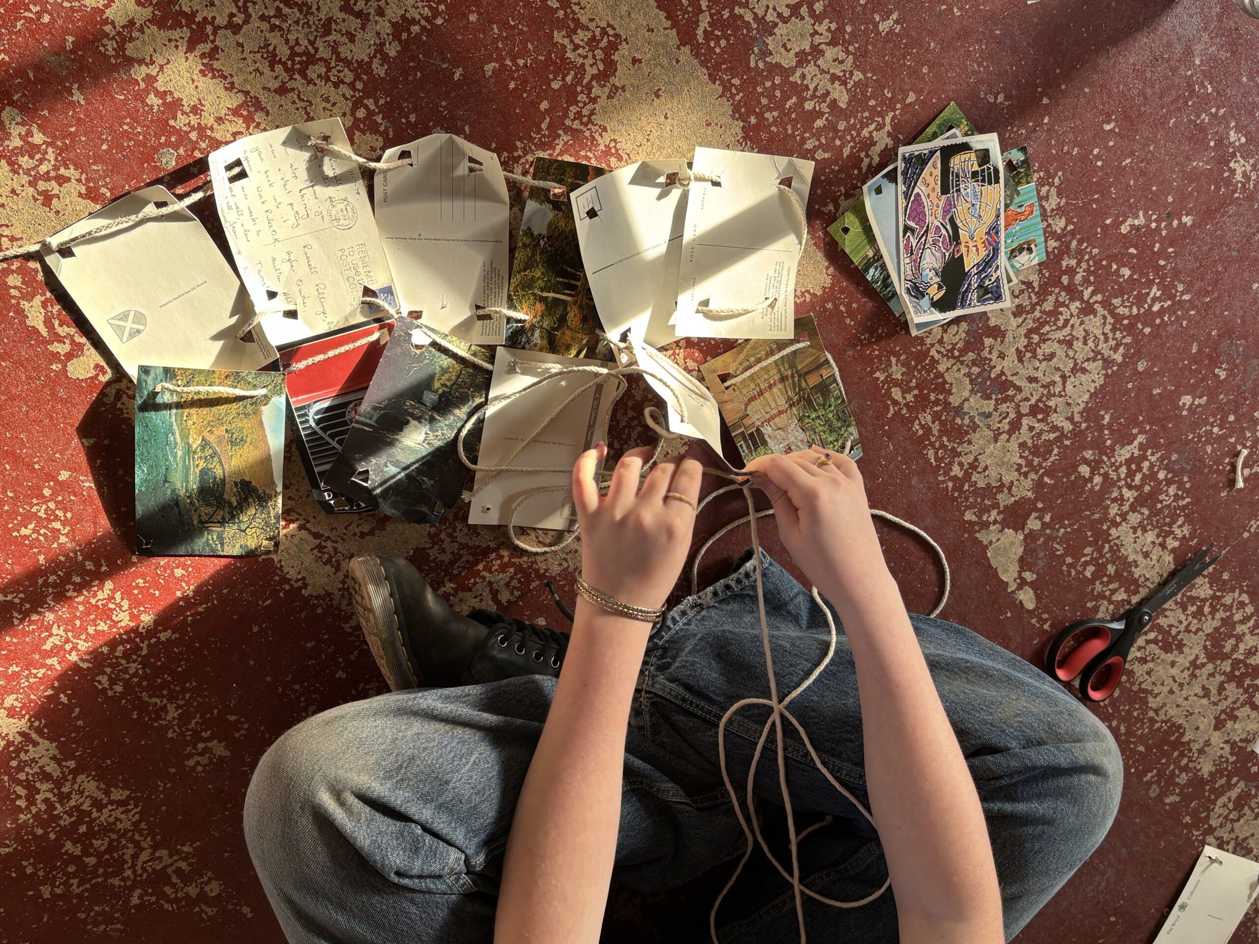 Girl making sculpture with string and postcards Girl making sculpture with string and postcards