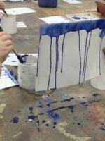 Blue paint dripping down paper.